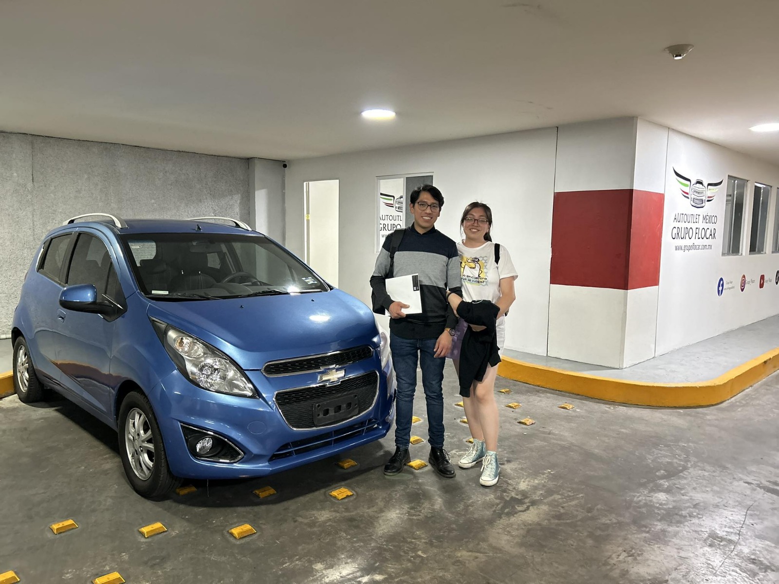 Coche deportivo plateado con capó abierto en un taller mecánico moderno.