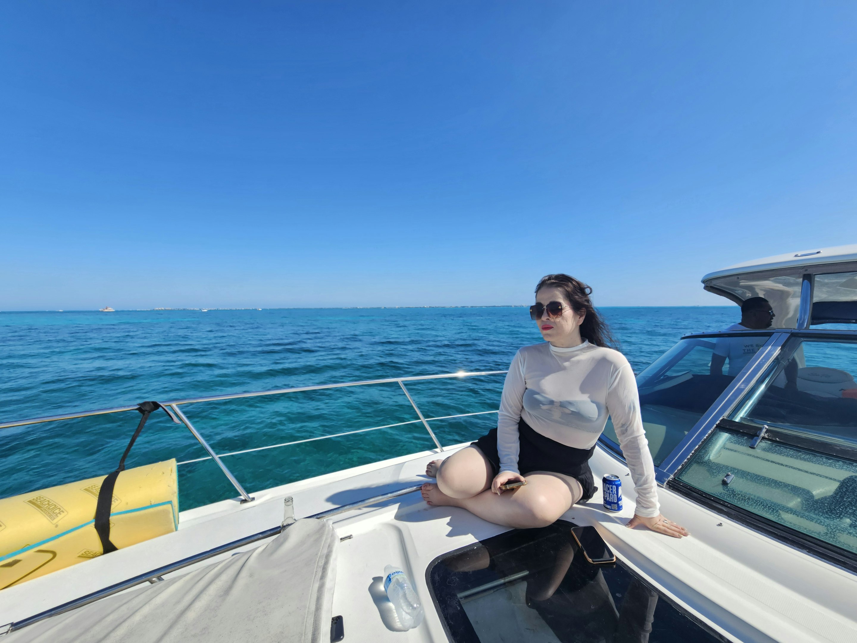 Playa tropical con palmeras, tumbonas de madera y agua azul cristalina con montañas al fondo.