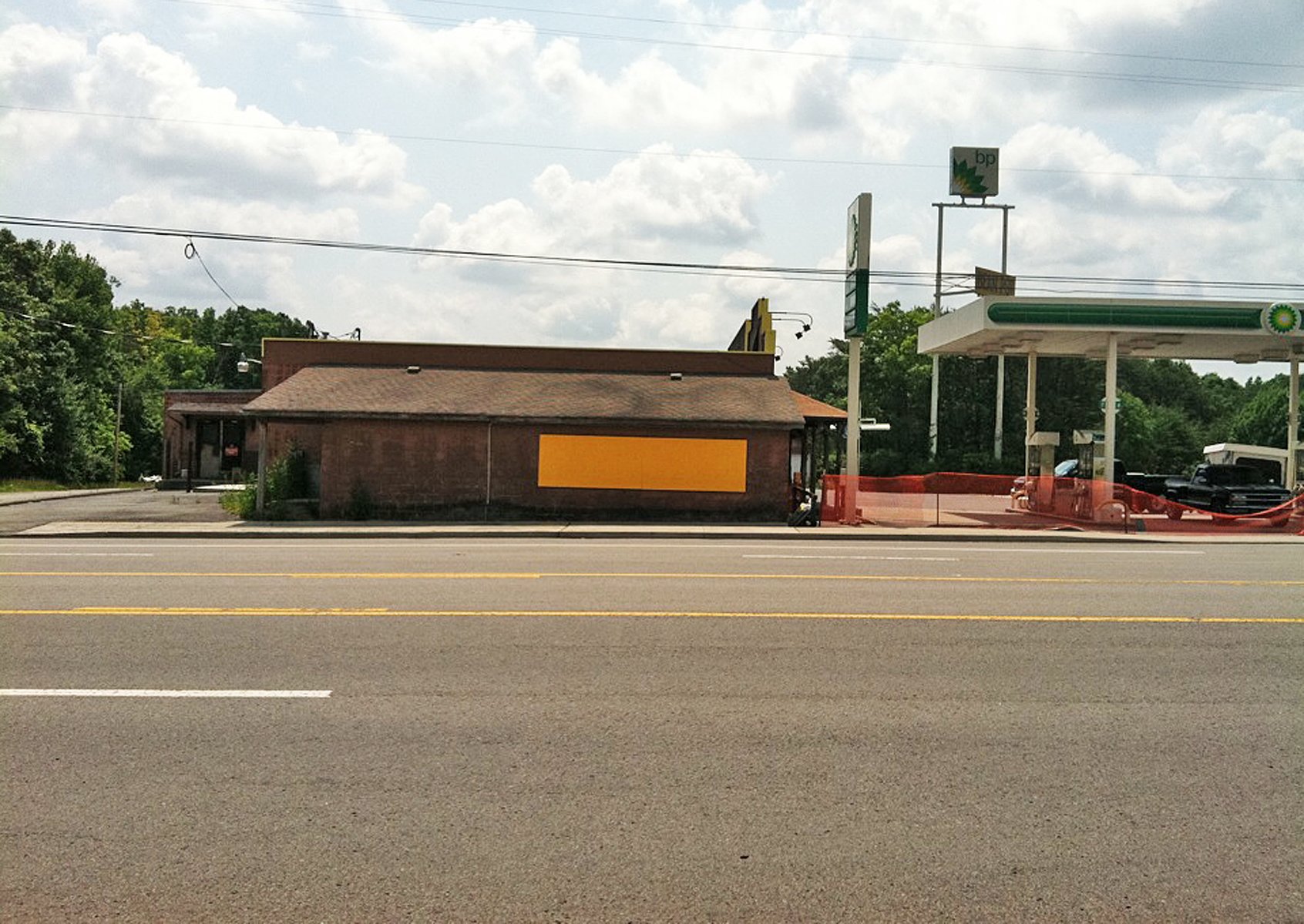 A minimalist yellow rectangle on a low brick building next to a BP gas station.