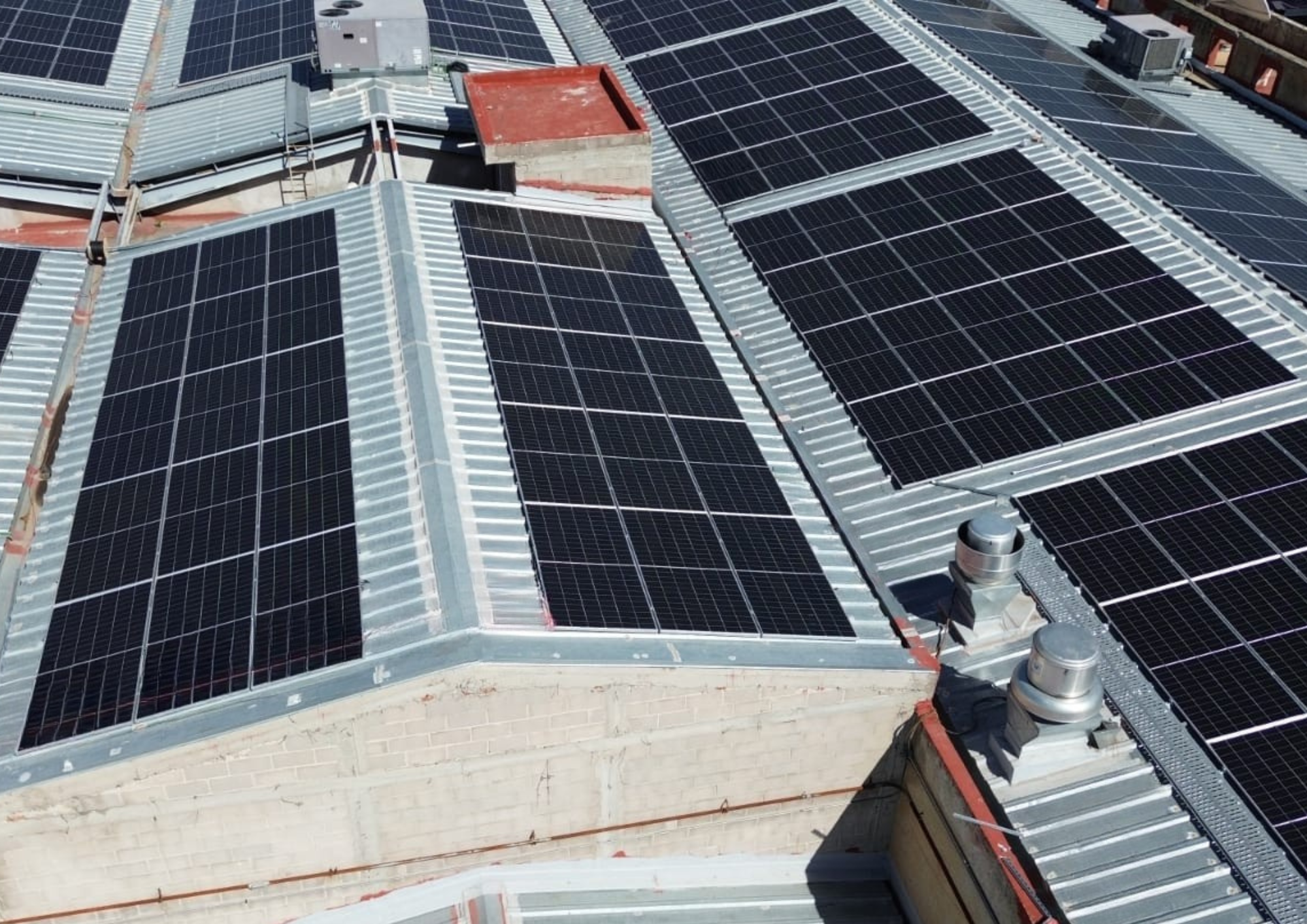 Paneles solares en un campo verde con cielo soleado y nubes al atardecer.