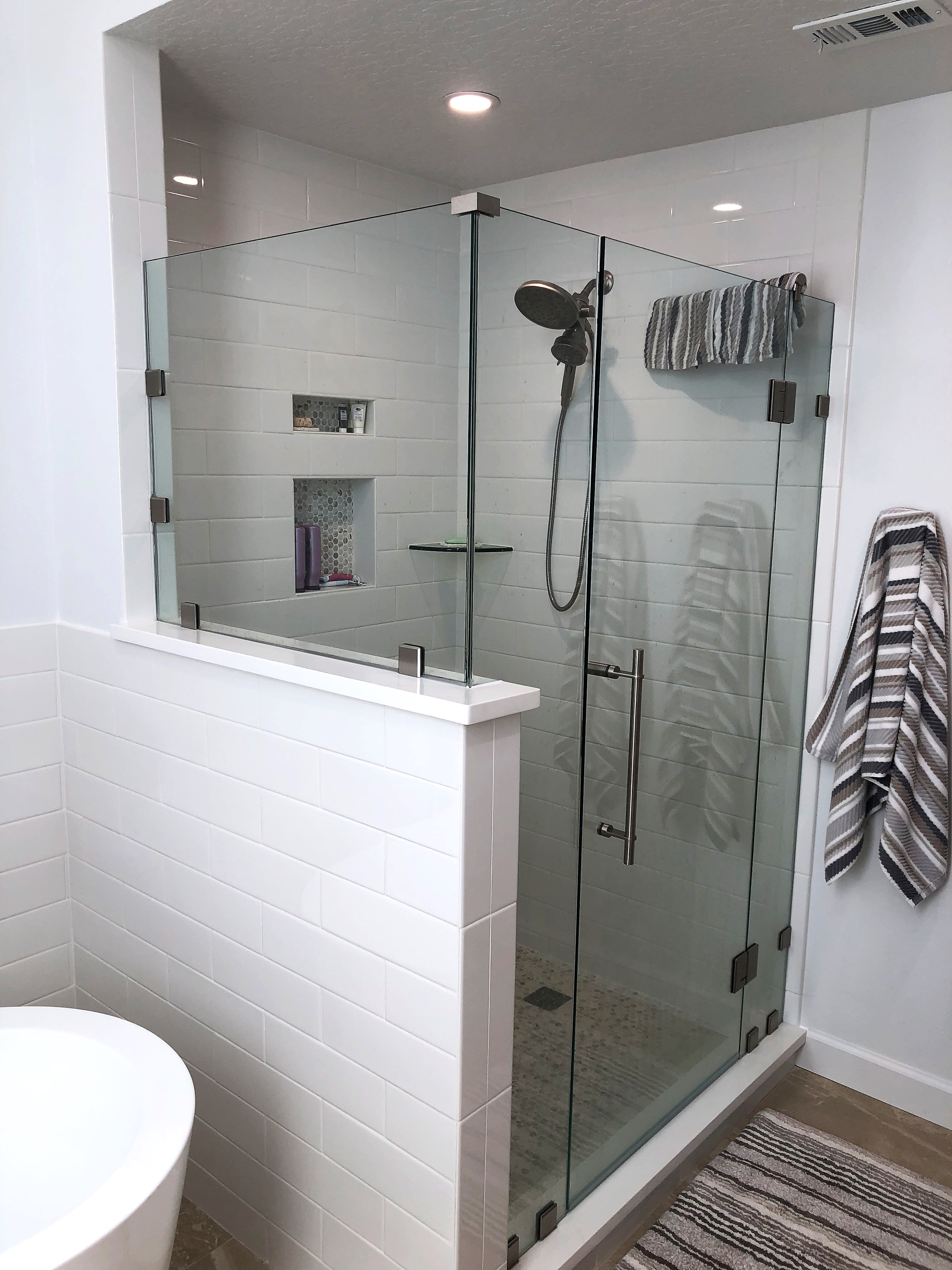 Stunning shower with classic subway tile, clear glass door, and panels with penny round tile on the shower floor.