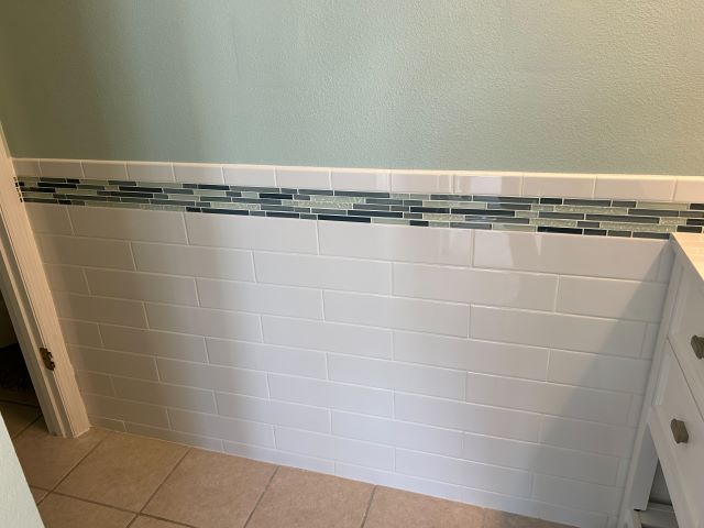 Beautifully tiled pool bath wall featuring glossy white subway tile and a band of Rain Blue glass mosaics.