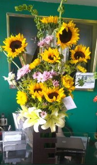 Arreglo de Girasol G9 con lilies y dos Vases cilindro de vidrio y madera.
$950