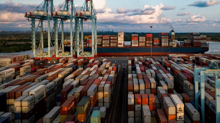 Almacén moderno con cajas de cartón y texto 'Logistics Services'. Amplio espacio y estanterías al fondo.