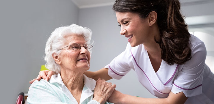 Smiling Nurse And Old Woman Patient At Wheelchair
