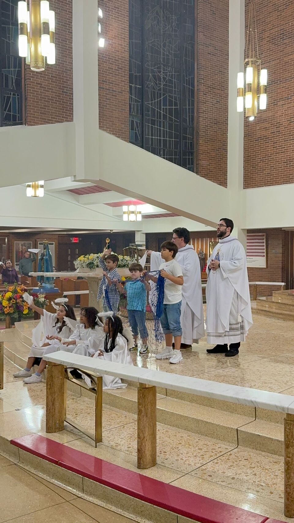Children and clergy in a church dressed in white robes during a religious ceremony.