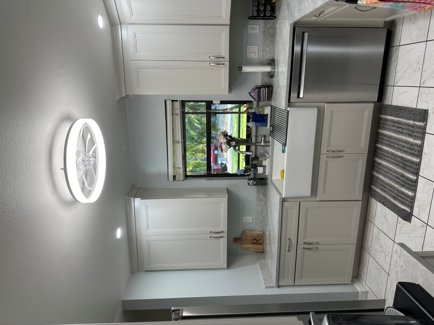 Bright and open kitchen featuring semi-custom Irish cream-painted cabinetry and a large farmhouse sink.