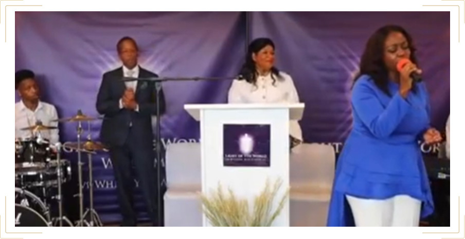 A woman dressed in blue singing into a microphone