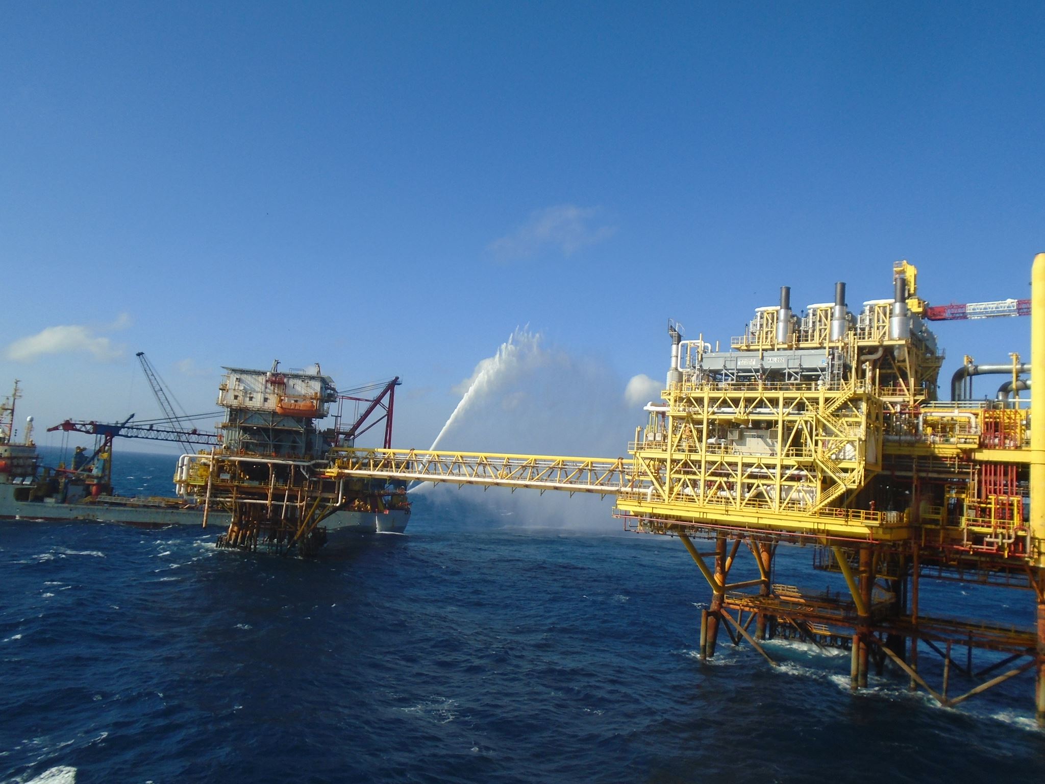 Plataforma petrolera en el océano con grúas y estructuras metálicas bajo un cielo despejado.