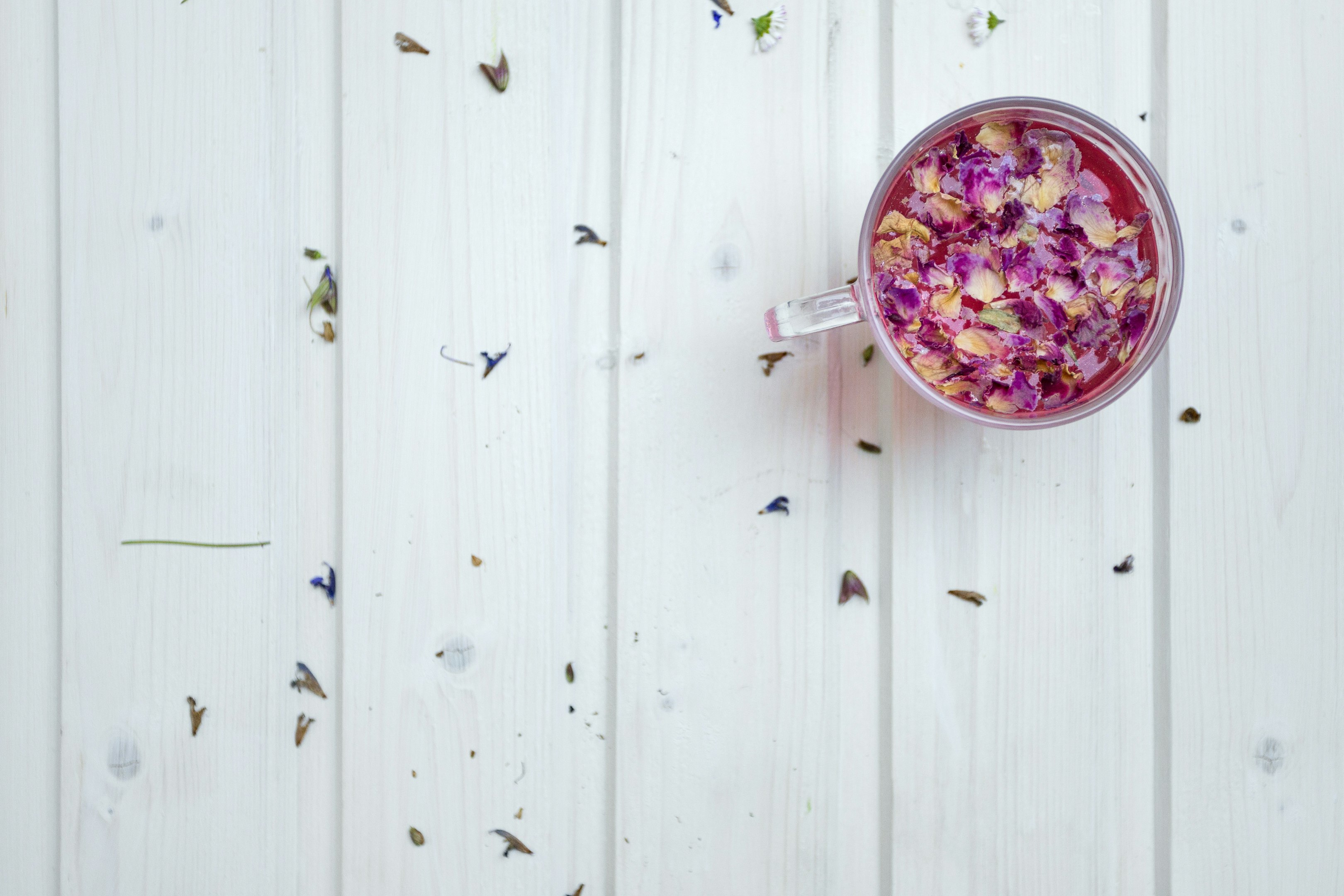 taza de vidrio transparente con cereal en superficie blanca