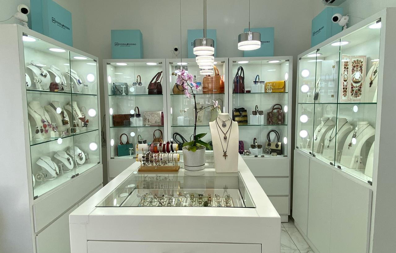 Interior de tienda elegante con mostrador curvo, estanterías iluminadas y decoración floral en la pared.