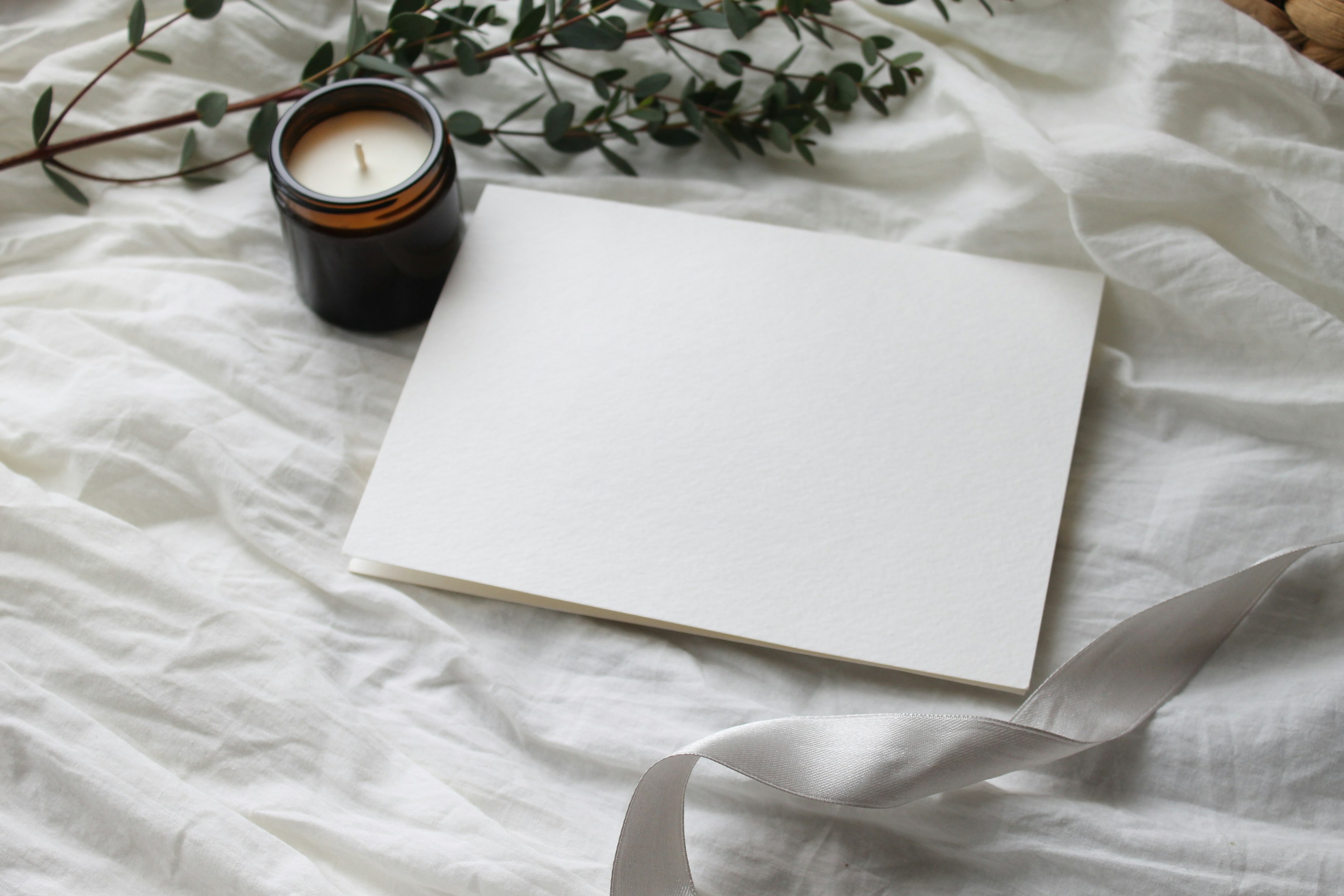 papel de impresora blanco junto a taza de cerámica negra sobre textil floral blanco y verde