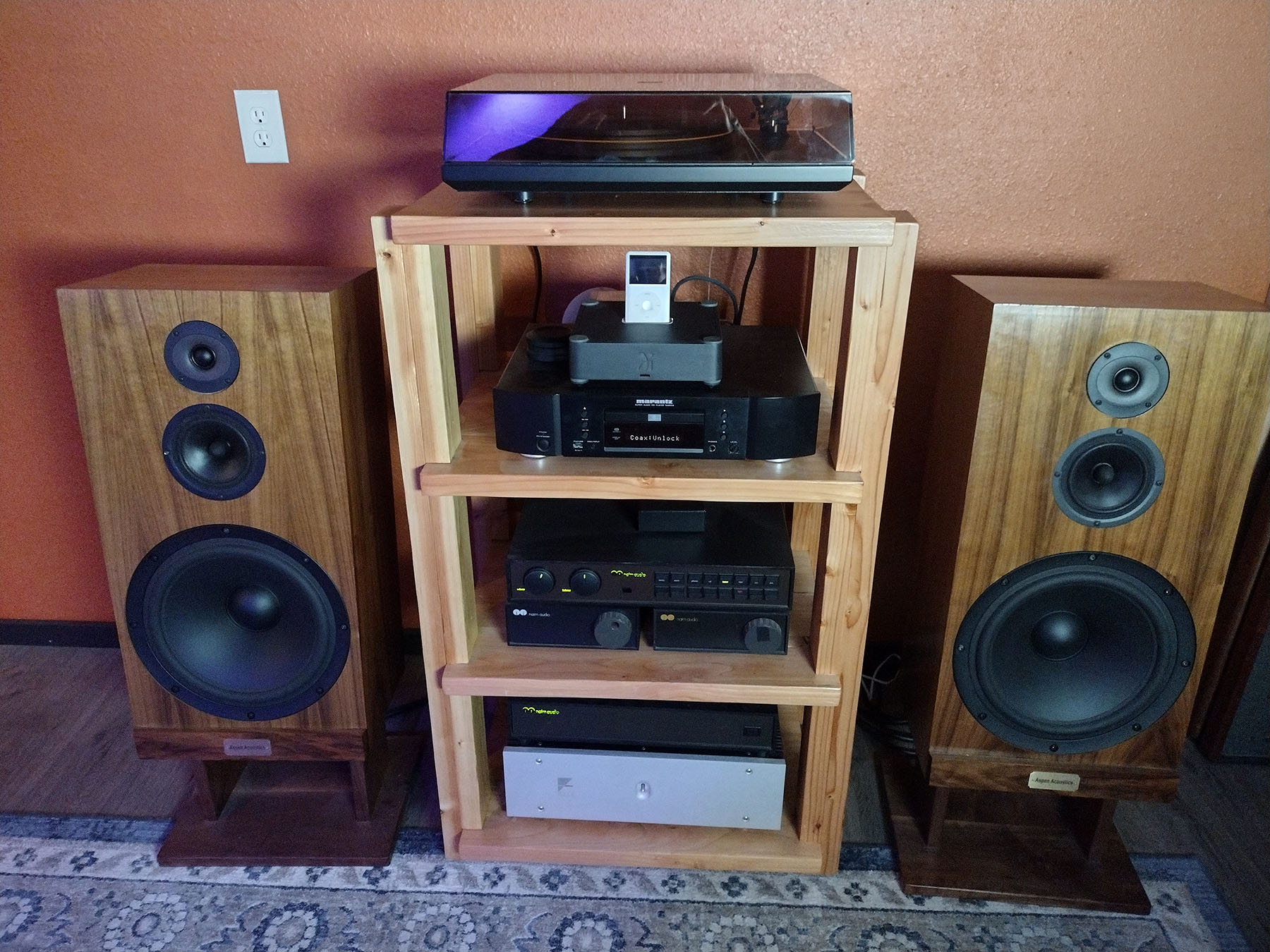 Pair of wooden bookshelf speakers with black woofers and tweeters on a modern media console in a bright living room