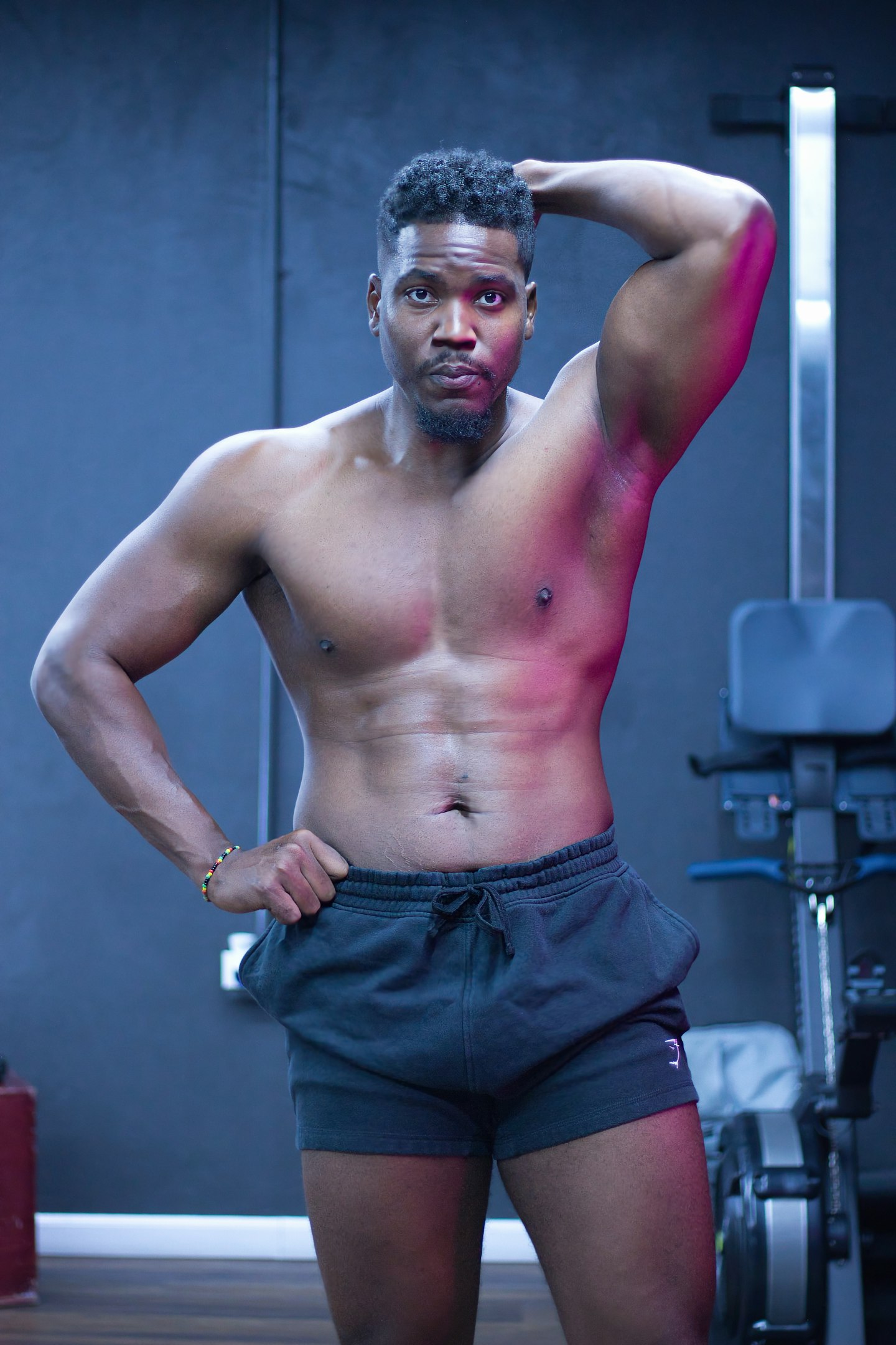 Muscular man posing shirtless in gym attire.