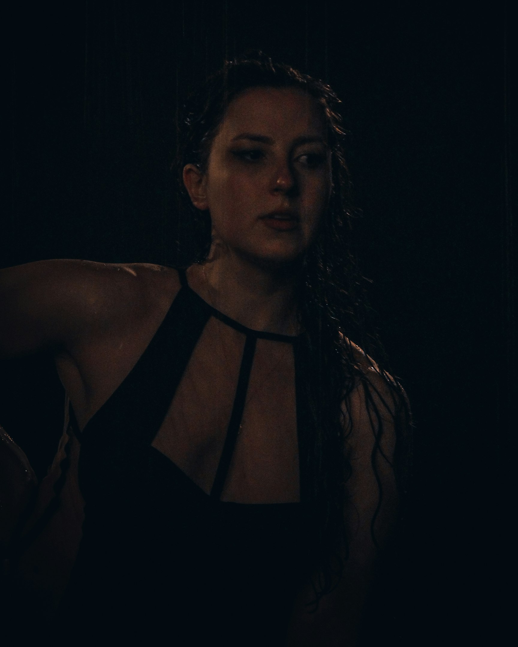 a woman standing in the dark wearing a halter top