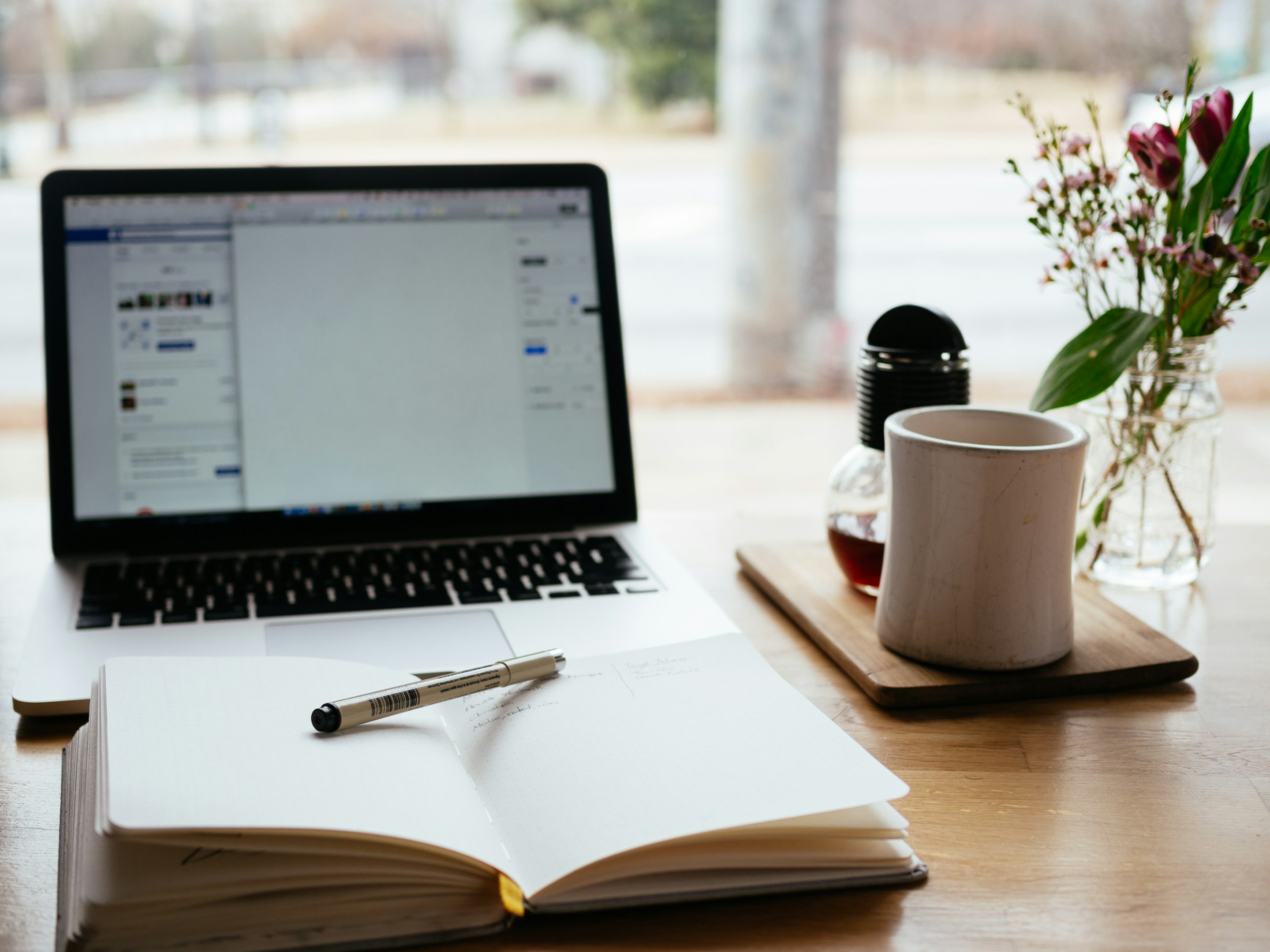 MacBook Pro cerca de un libro abierto blanco