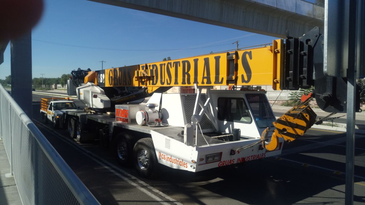 Grúa industrial amarilla y blanca aparcada junto a una carretera.