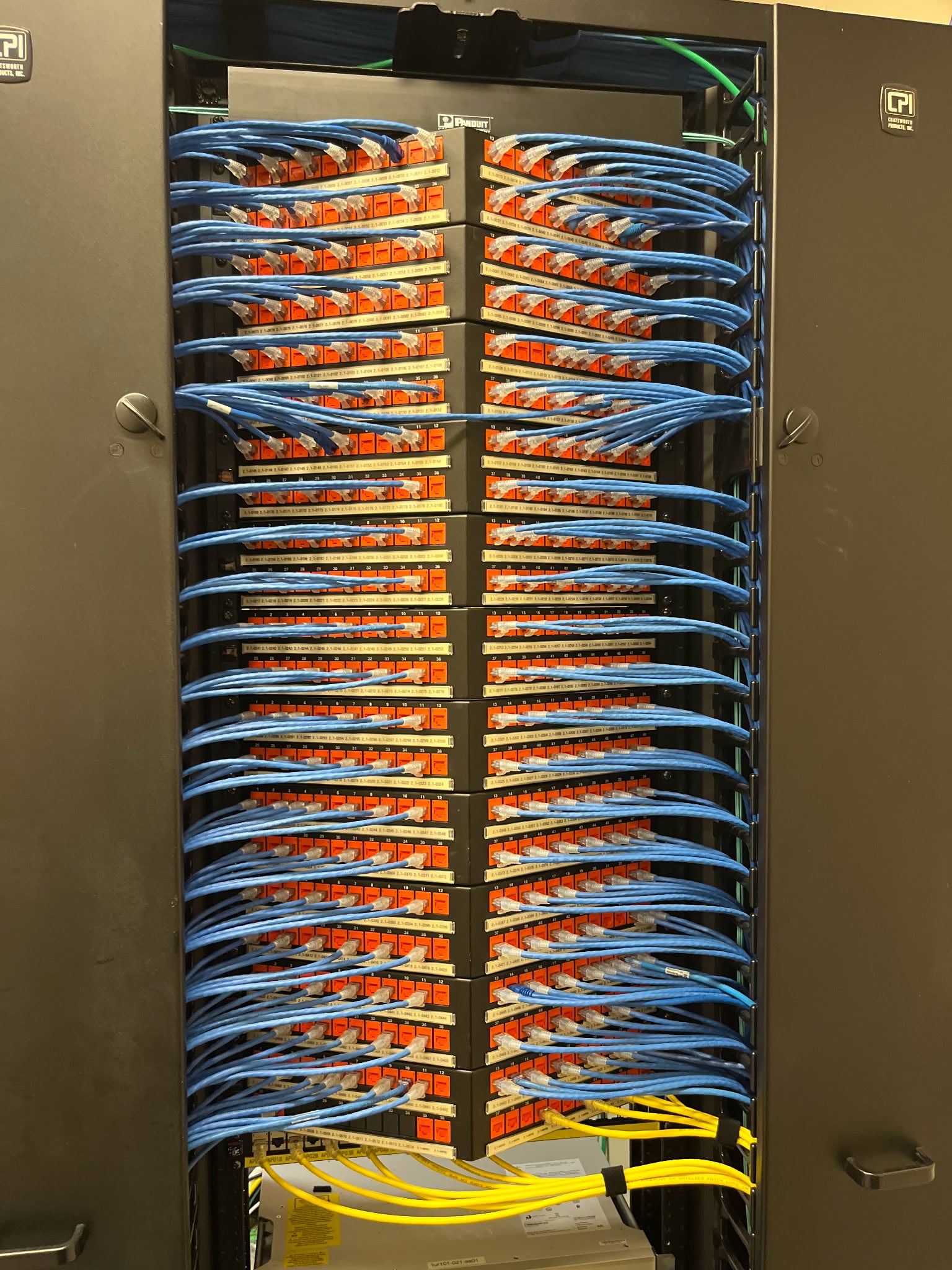 Modern data center with a central monitor displaying network analytics surrounded by server racks and cables, reflecting advanced technology infrastructure.