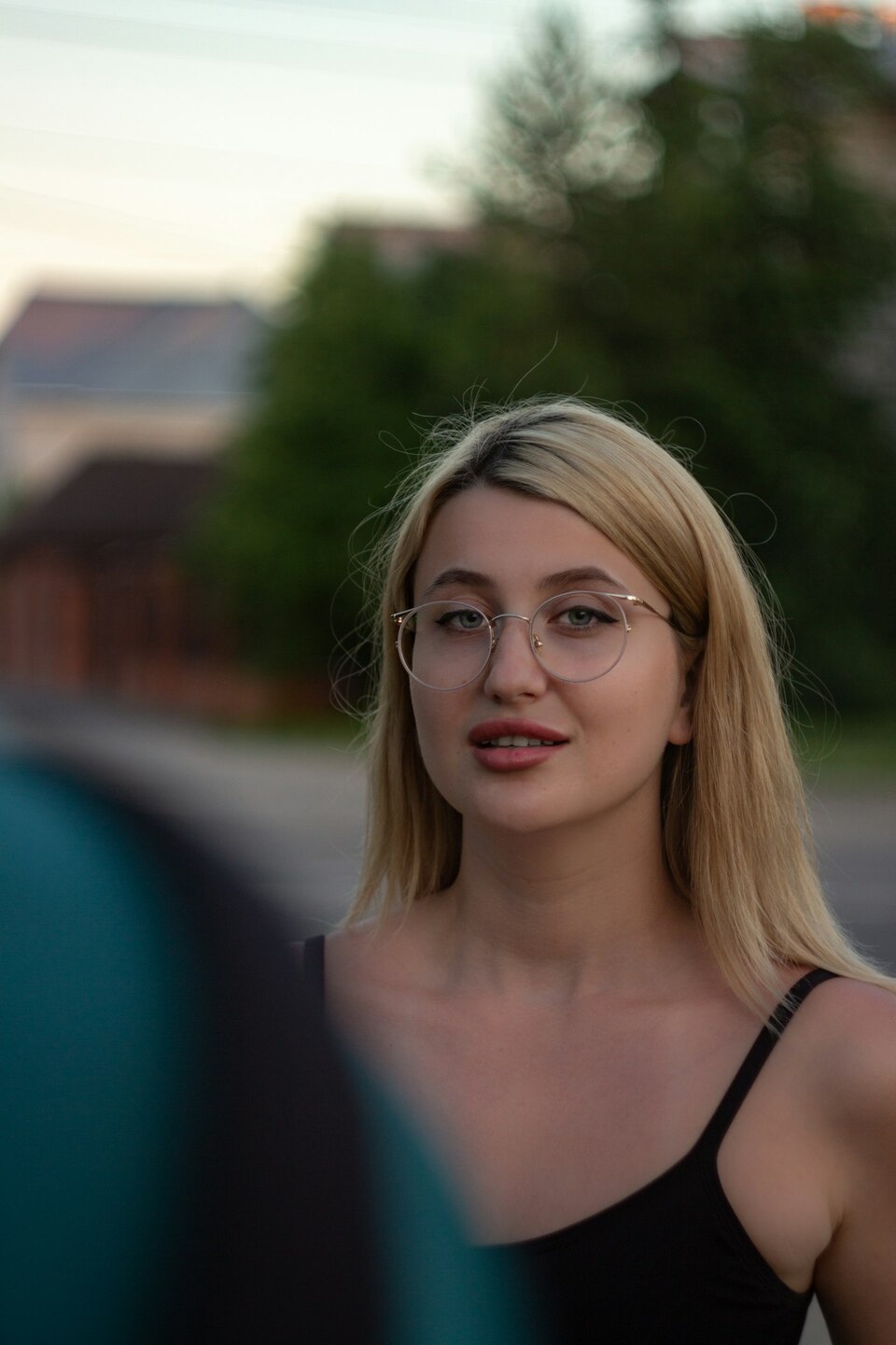 Mujer joven con gafas y cabello rubio sonriendo al aire libre. Mujer joven con gafas y cabello rubio sonriendo al aire libre.