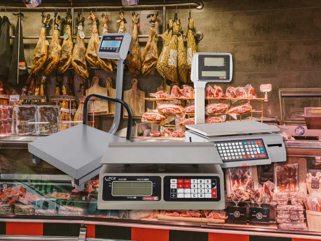 Refrigerador comercial con puertas de vidrio lleno de bebidas y alimentos en una cocina moderna iluminada por el sol.