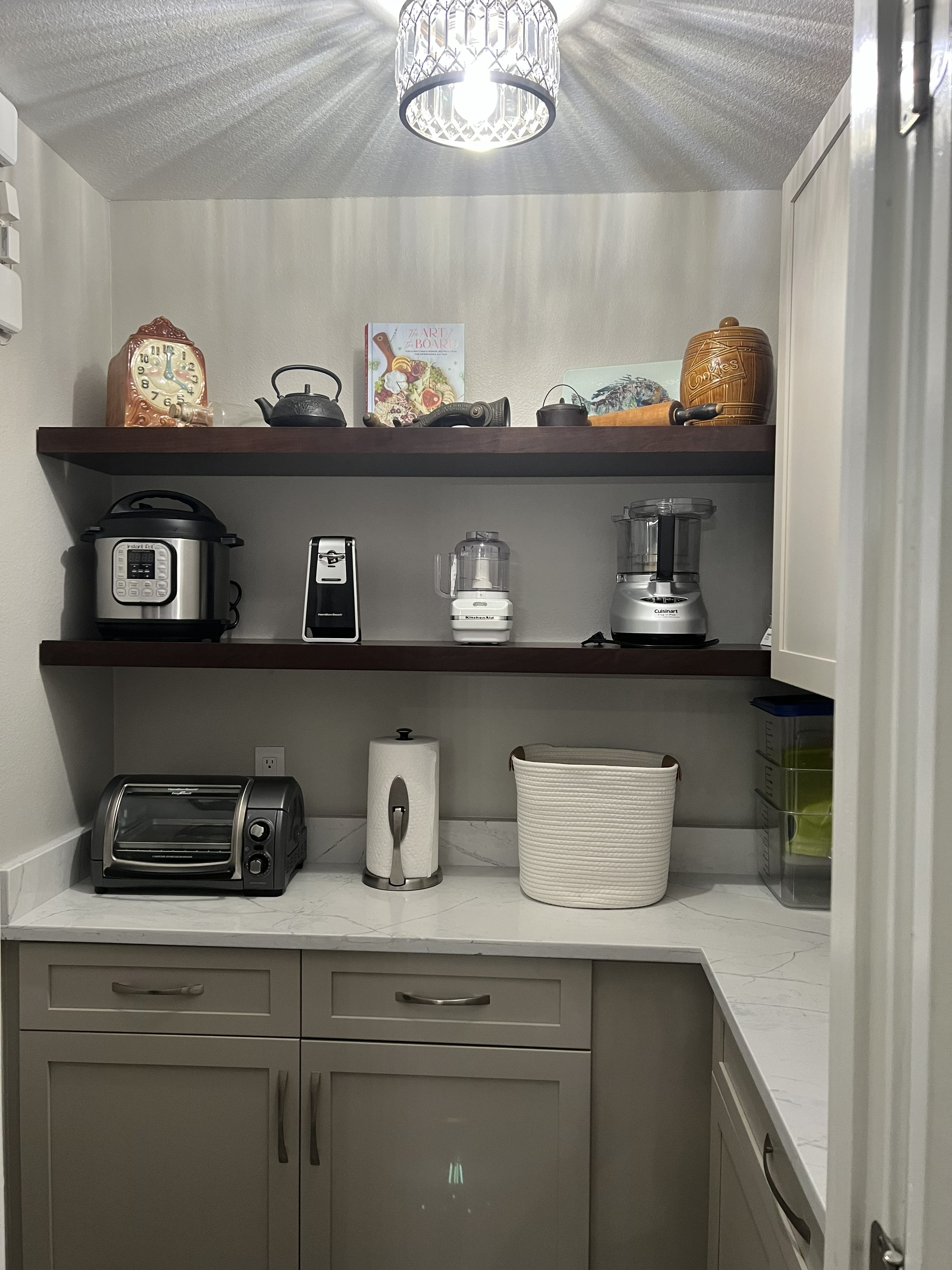 The Ginger Snap-stained cherry wood floating shelves and painted cabinetry create a stylish and organized pantry area.