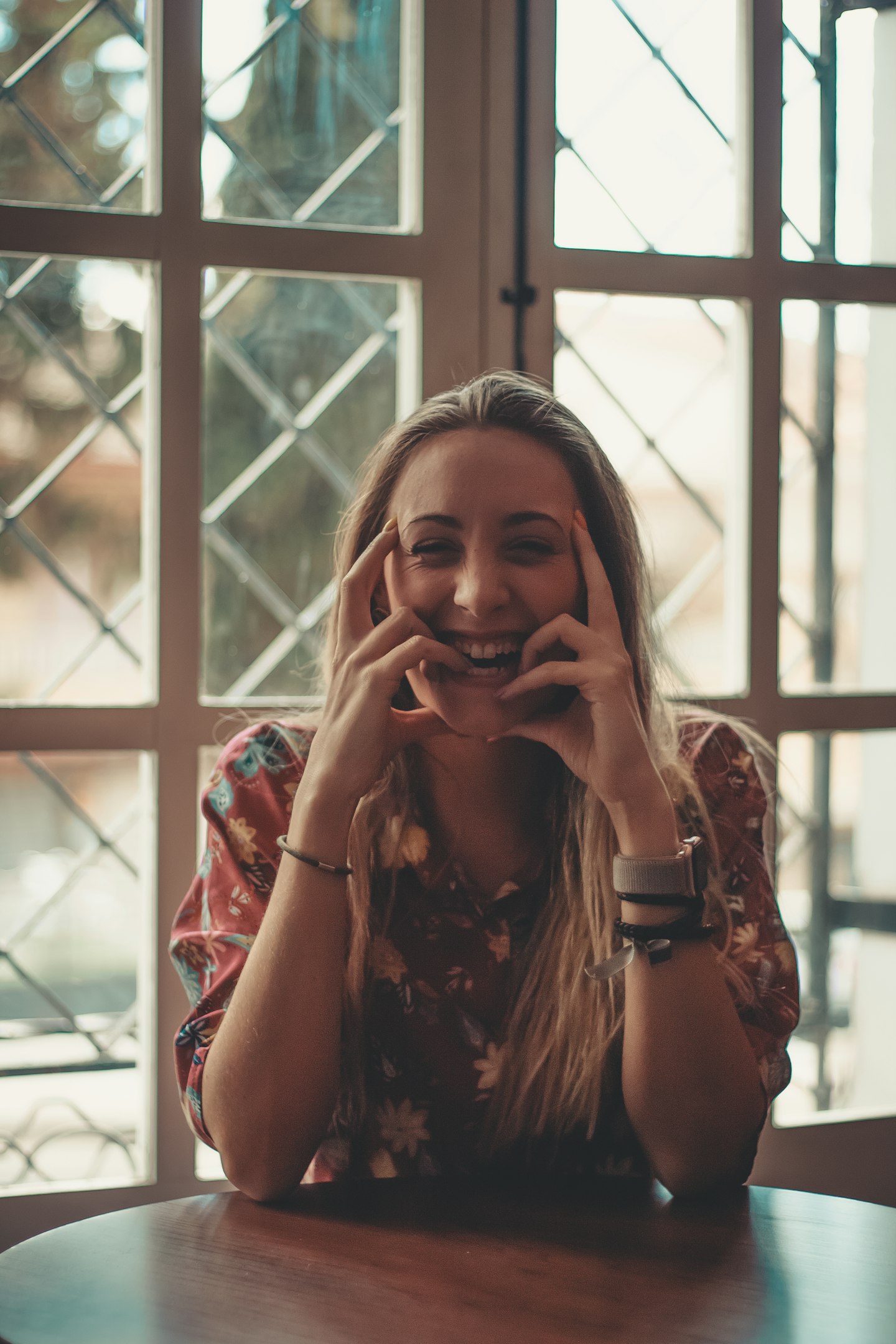 woman wearing maroon and white floral blouse sitting on chair