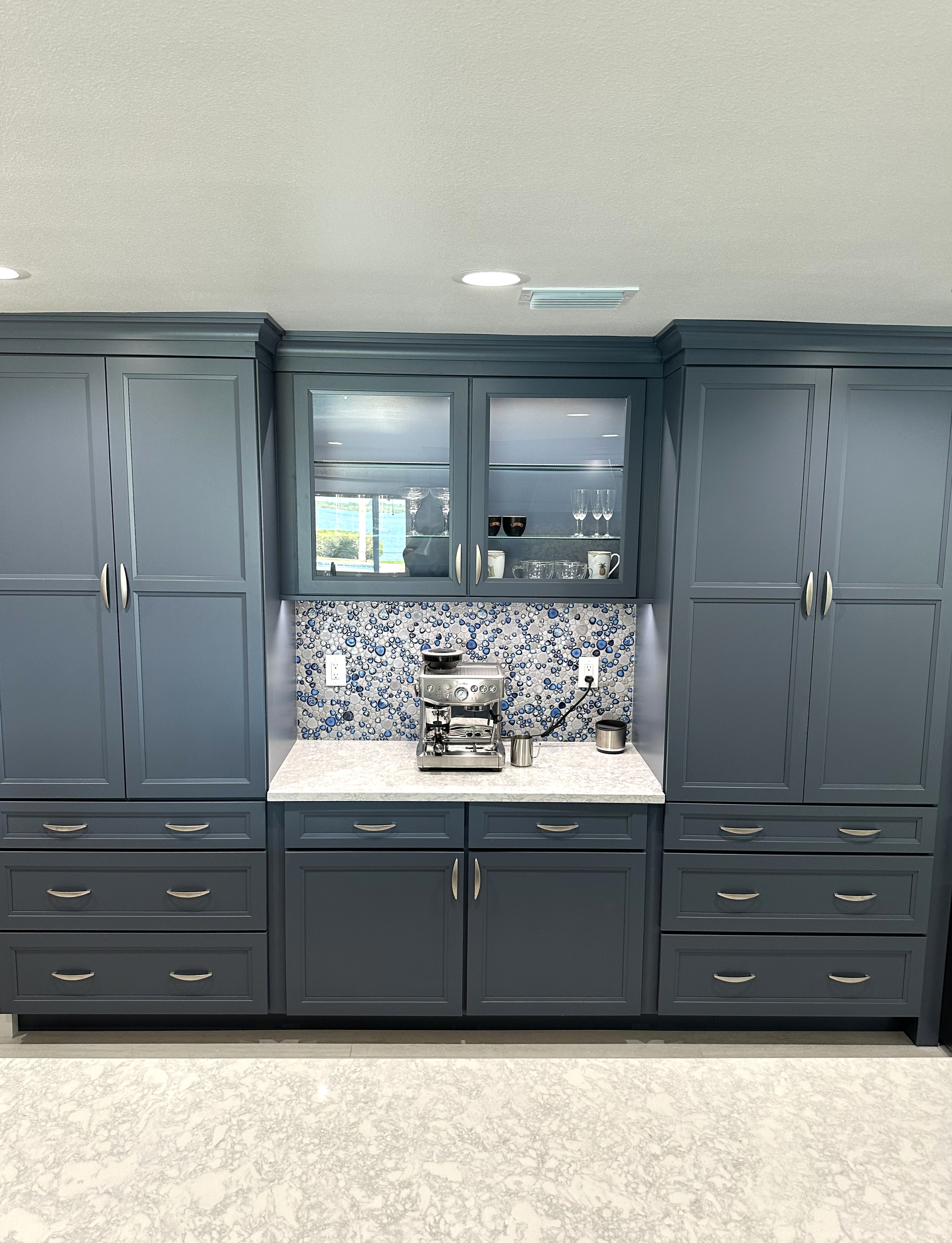 A stunning coffee bar area featuring ample additional storage and accented by a beautifully coordinated backsplash that seamlessly ties the entire space together.