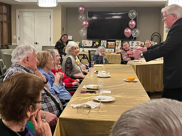 Chuck entertaining a group of seniors who are smiling and laughing. Chuck entertaining a group of seniors who are smiling and laughing.