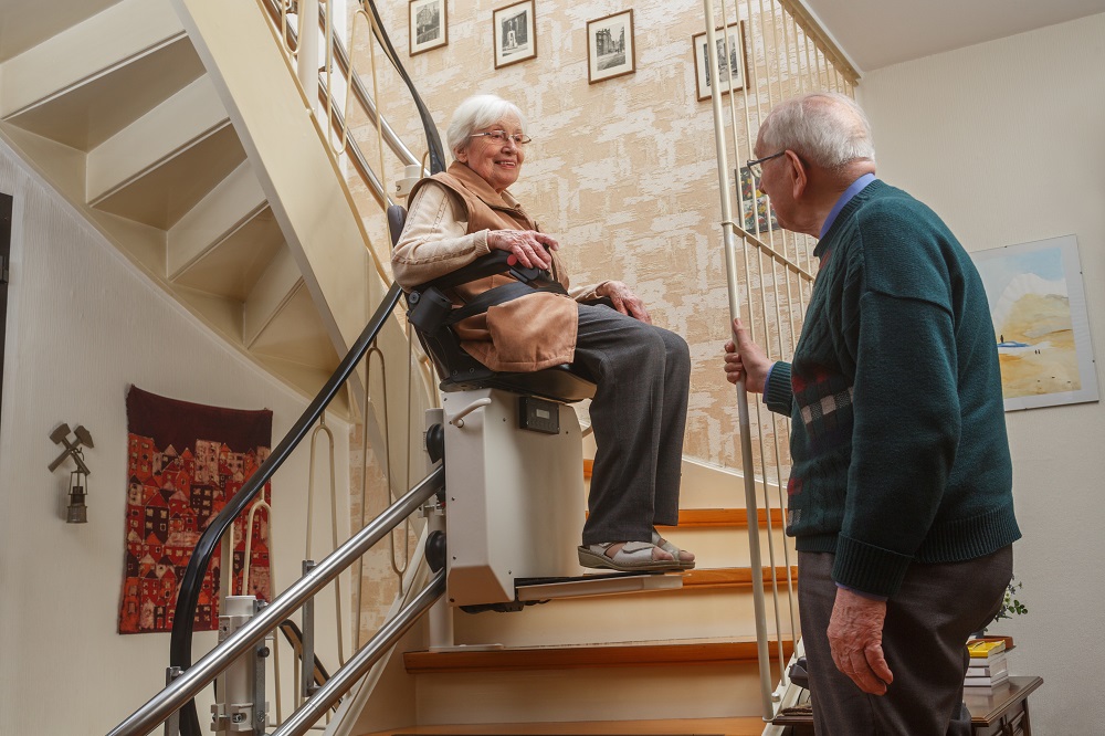 Smiling Older Woman Riding StairLift Upstairs