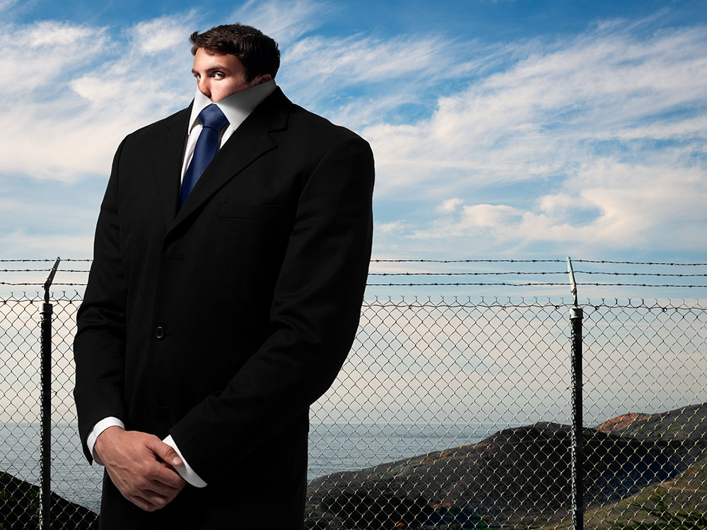 Surrealistic photo-illustration of man in a business suit whose head is pulled down into the collar of his shirt.