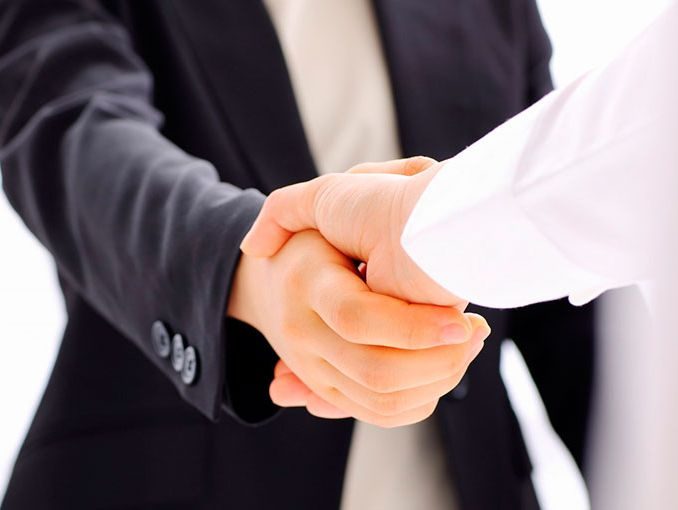  Control de acceso en un entorno corporativo donde dos personas con traje estrechan la mano, simbolizando acuerdos profesionales, confianza empresarial y procesos de acceso autorizados dentro de instalaciones seguras