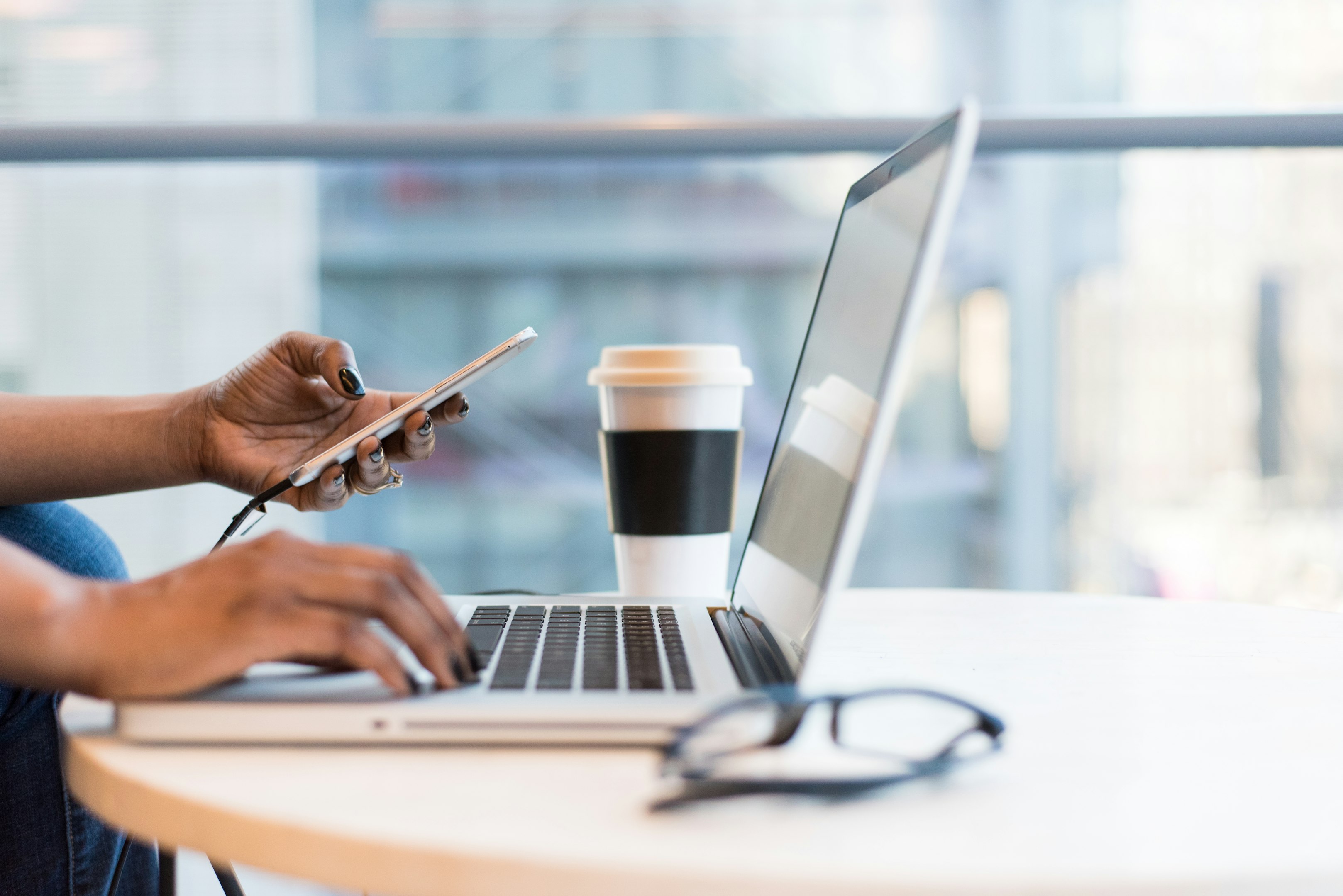person using smartphone and MacBook
