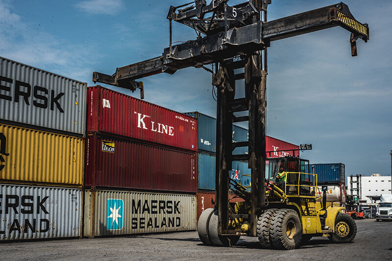 Camión blanco de carga circulando por una autopista junto a montañas al atardecer.