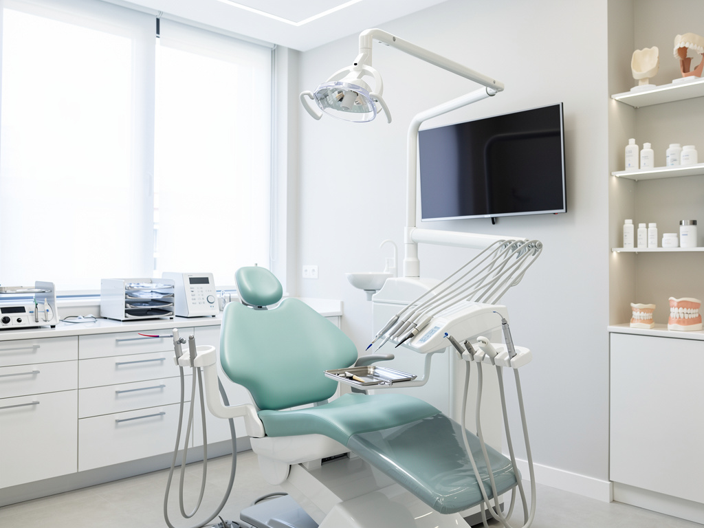 Clínica dental moderna con sillón odontológico, lámpara, instrumental y pantalla en consultorio luminoso