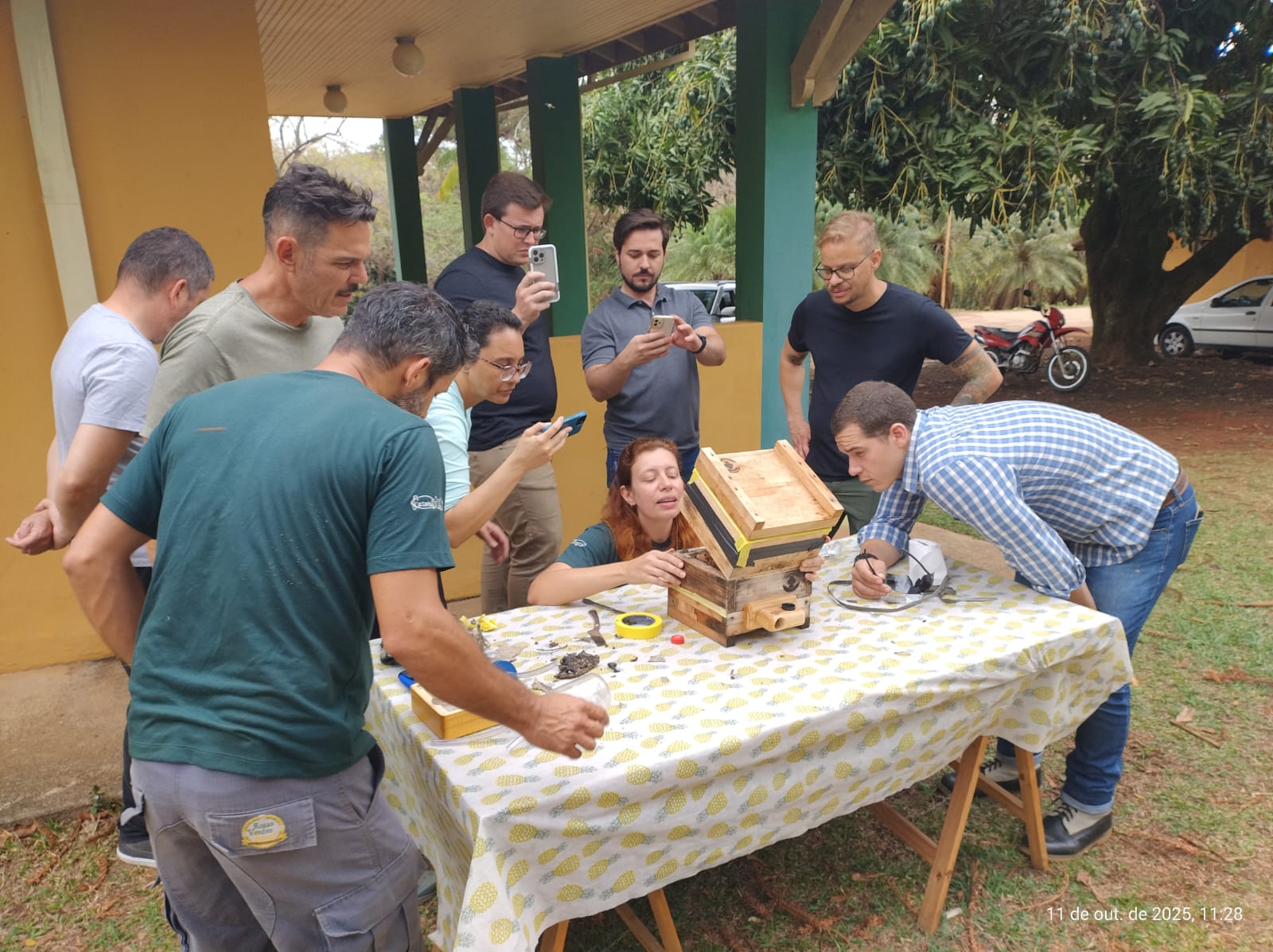 Crianças reunidas ao redor de um mapa, explorando a natureza em um ambiente externo sob a sombra de folhas grandes. Crianças reunidas ao redor de um mapa, explorando a natureza em um ambiente externo sob a sombra de folhas grandes.