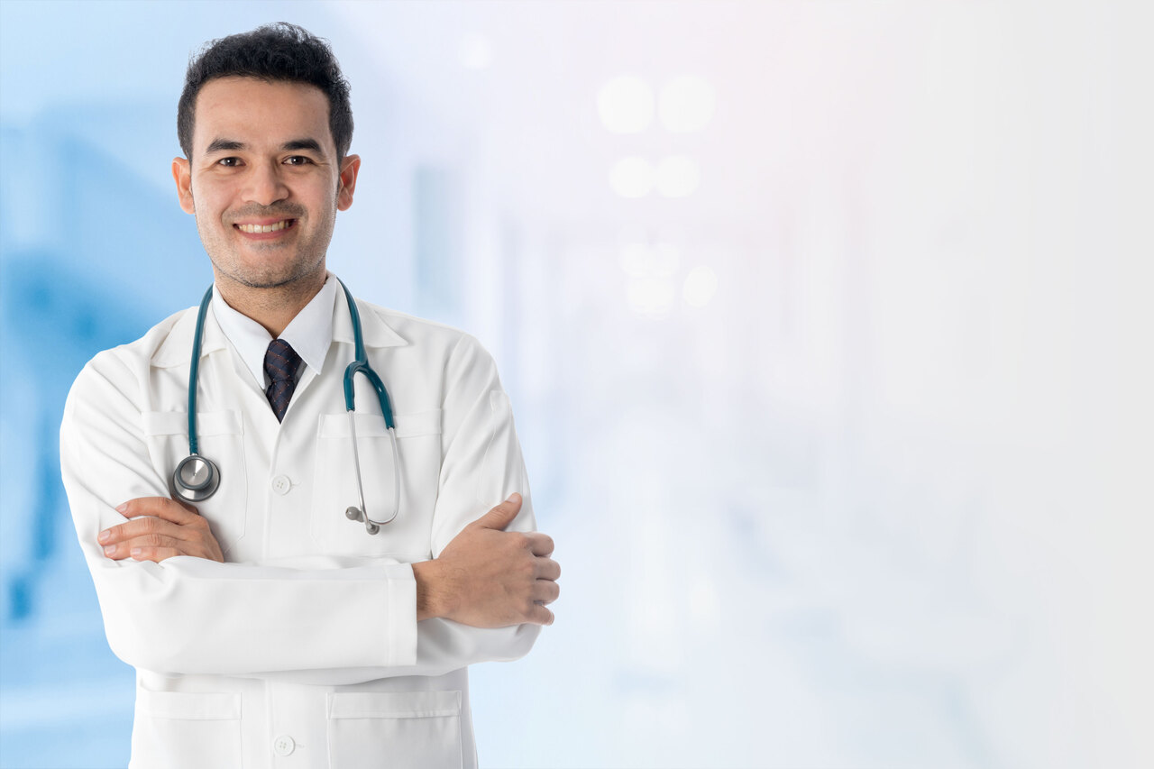 Médico sonriente con estetoscopio en hospital luminado.