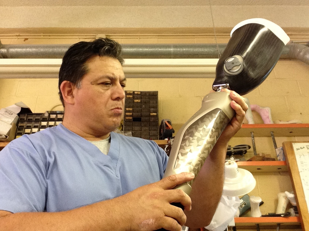 Orthotics technician examining a carbon fiber prosthetic leg socket in a workshop