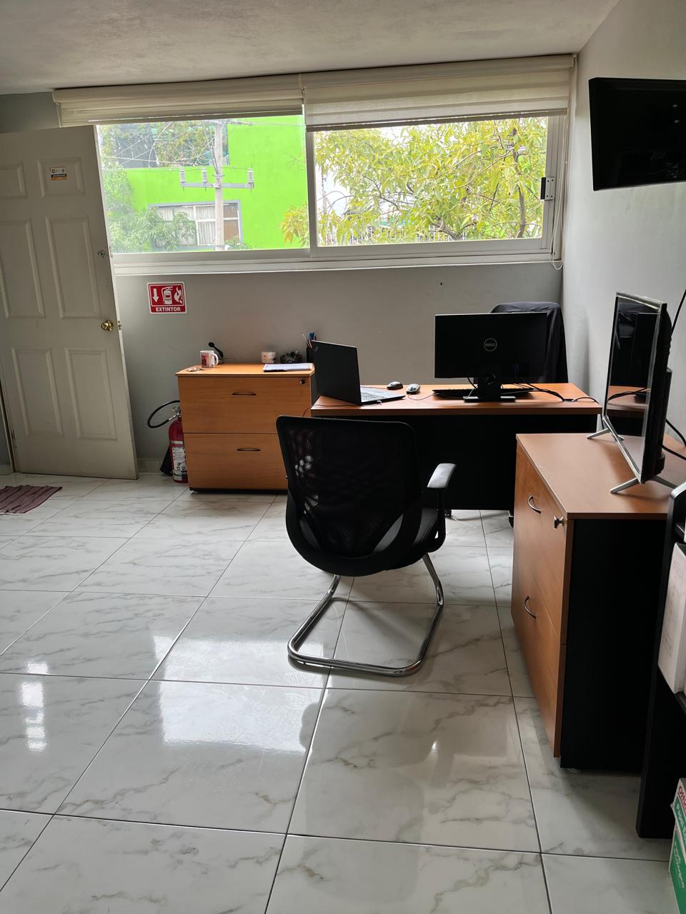 Oficina moderna con suelo de mármol, escritorio con ordenador y silla, luz natural entrando por la ventana.