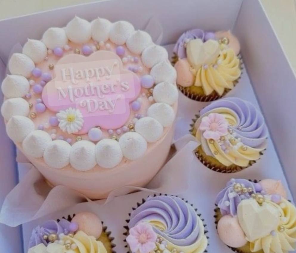 A pastel-colored Mother's Day cake with decorative frosting and five matching cupcakes in a gift box.