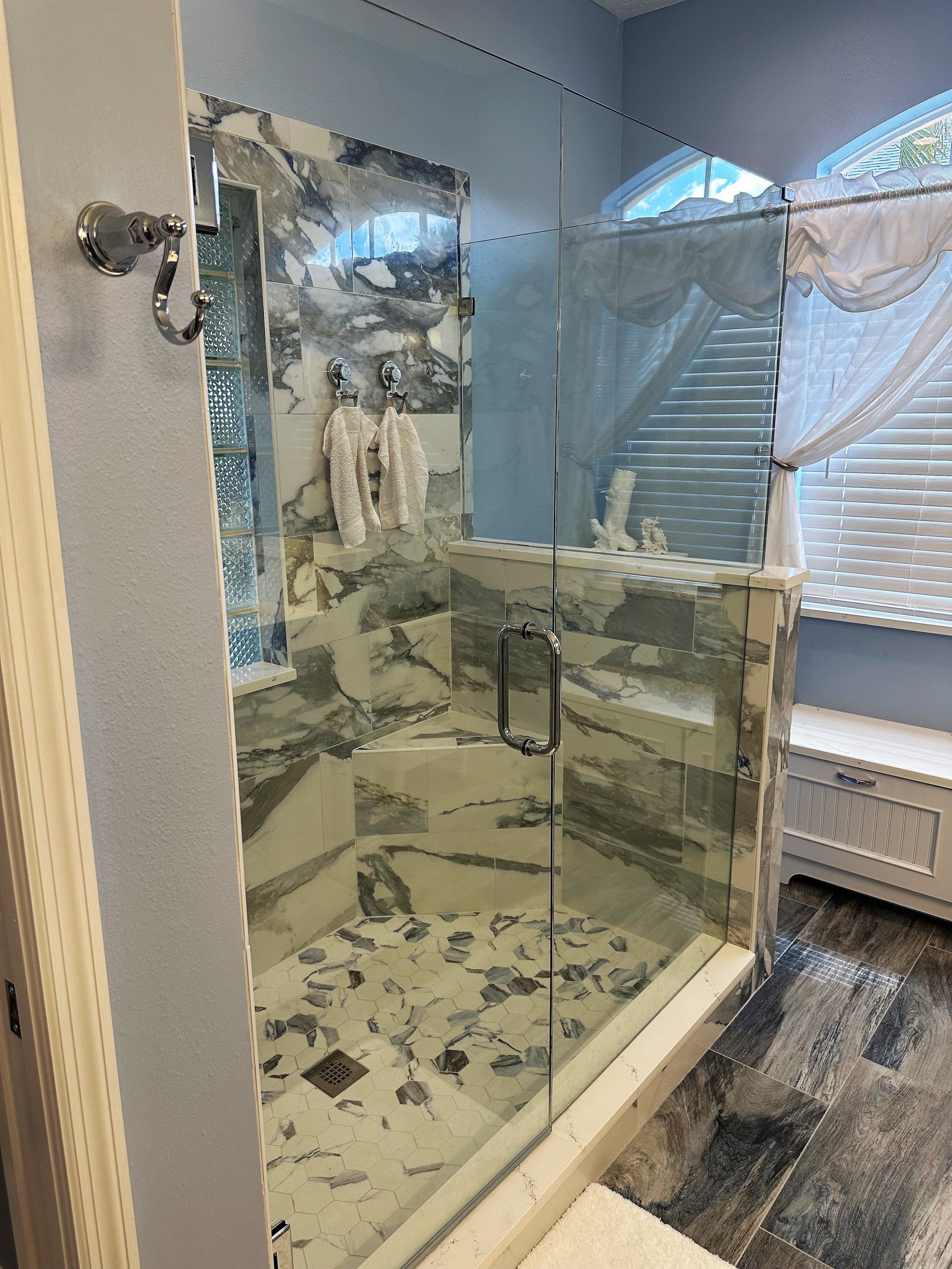 Clear heavy glass panels and door frame out this large walk-in shower with matching shower bench.