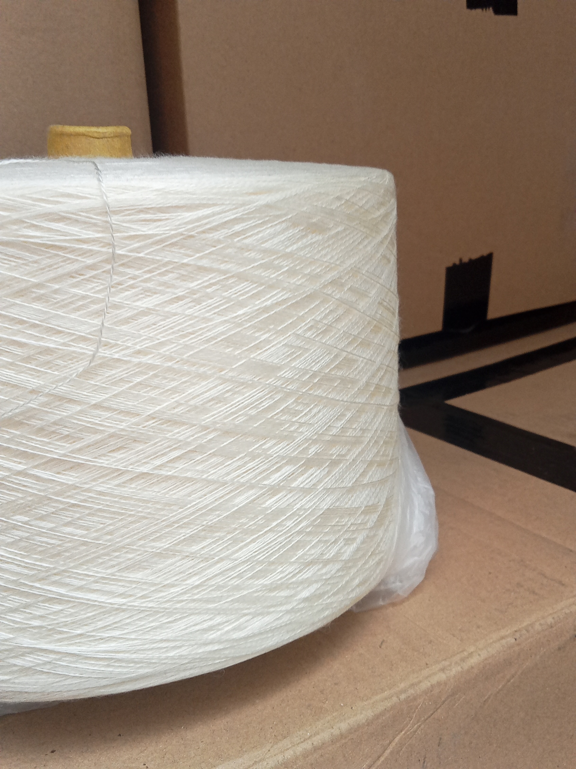 Bobina de hilo blanco sobre cajas de cartón.