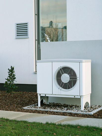 A heat pump outside of a white building