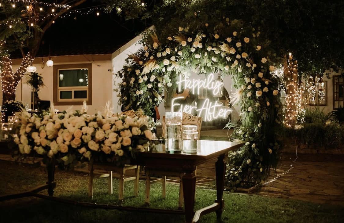 Interior de una floristería moderna con estanterías llenas de flores coloridas, como gerberas y crisantemos, iluminadas por luz natural.