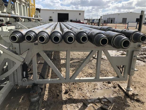 Obrero de construcción con casco junto a maquinaria pesada en obra ferroviaria urbana con grúas y rascacielos al fondo Obrero de construcción con casco junto a maquinaria pesada en obra ferroviaria urbana con grúas y rascacielos al fondo