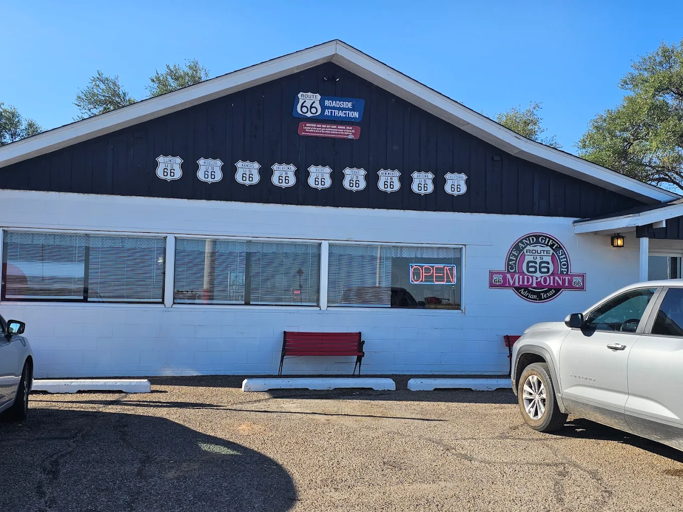 Scenic view of a tree-lined road with parked RVs under blue sky with clouds.