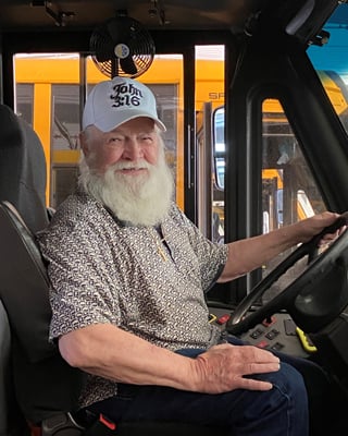 David started with us back in 2004. Currently he drives a big bus and over the years has delivered kids to & from Bayview, Eastern Carver County, Laketown, Southview, St Joes and Trinity.
He likes all the kids but says the younger ones have better stories and as you may have guessed; he dresses as Santa every Christmas season which all the kids really enjoy!
He likes driving a bus so much that in 2015, he convinced his wife Shirley (see next pic) to start driving for us as well! In the warmer months when not driving or being Santa, he enjoys playing golf and fishing.