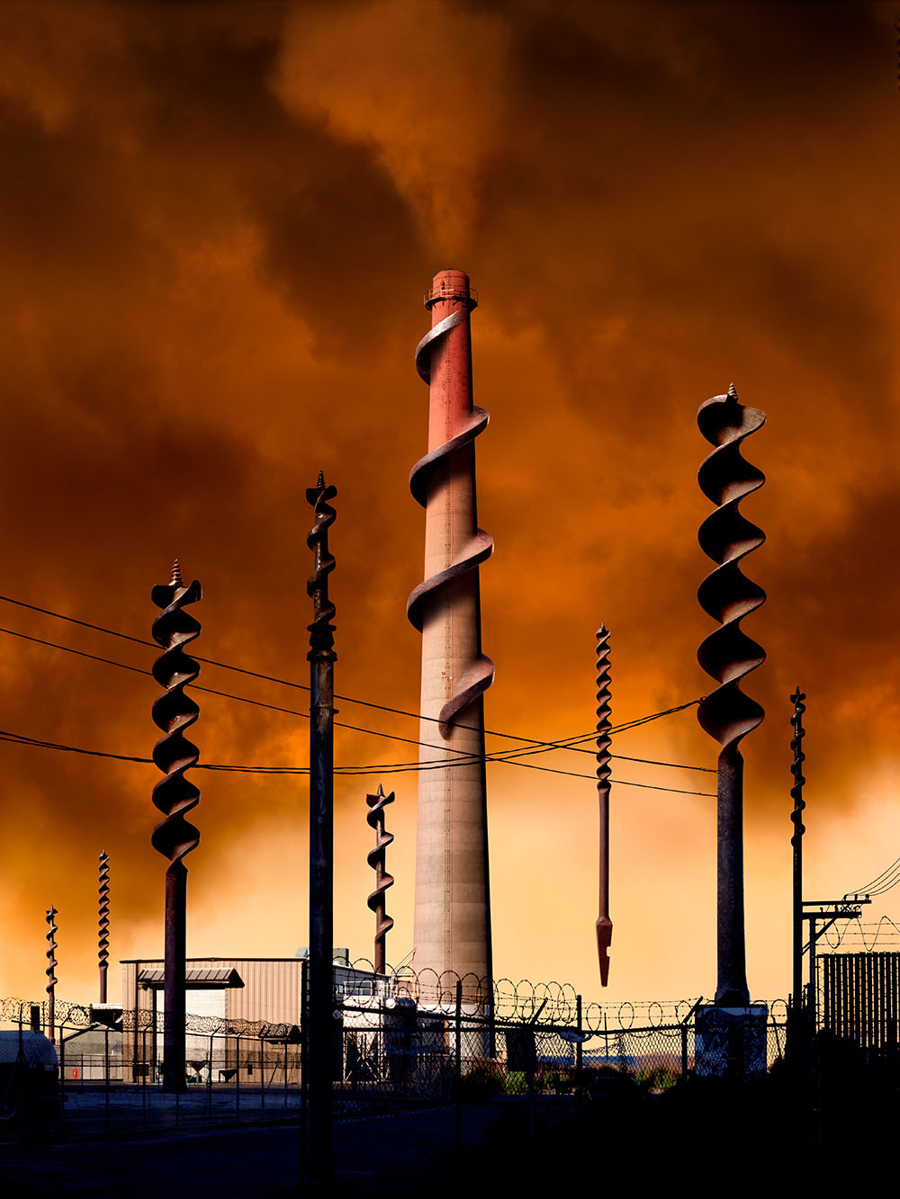 Fantastical, dark industrial landscape centered on a large smokestack with the flutes of a drill bit wrapped around its form.