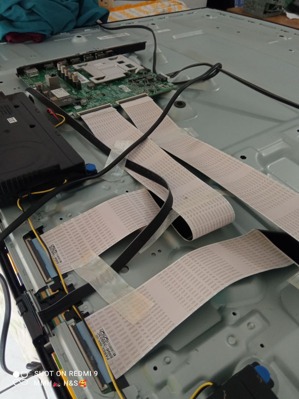 Hombre con camisa azul y guantes revisando documentos en una computadora portátil en una oficina moderna con equipo de impresión.