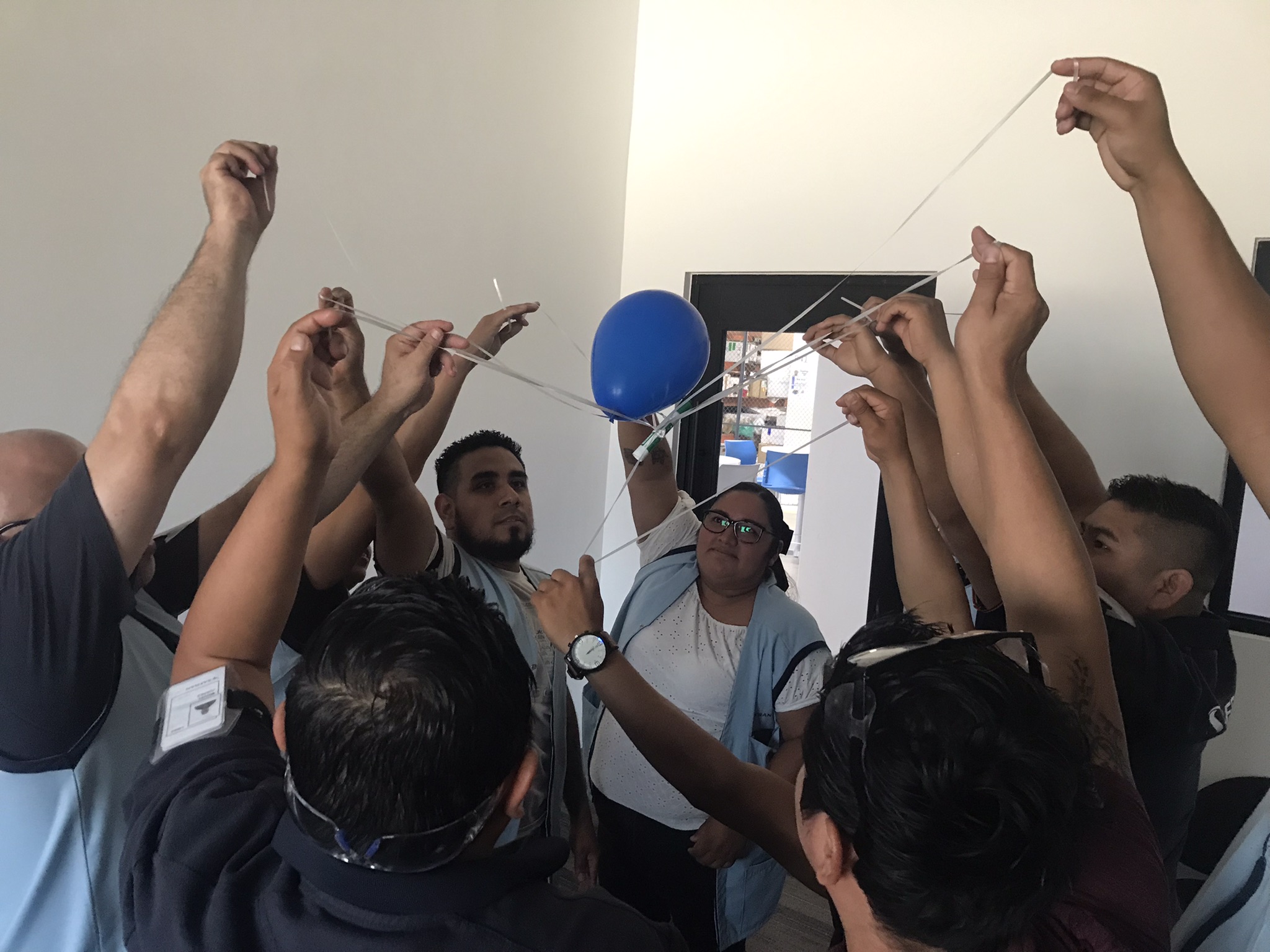 Grupo de personas participan en una actividad de equipo con un globo azul y cuerdas. Grupo de personas participan en una actividad de equipo con un globo azul y cuerdas.