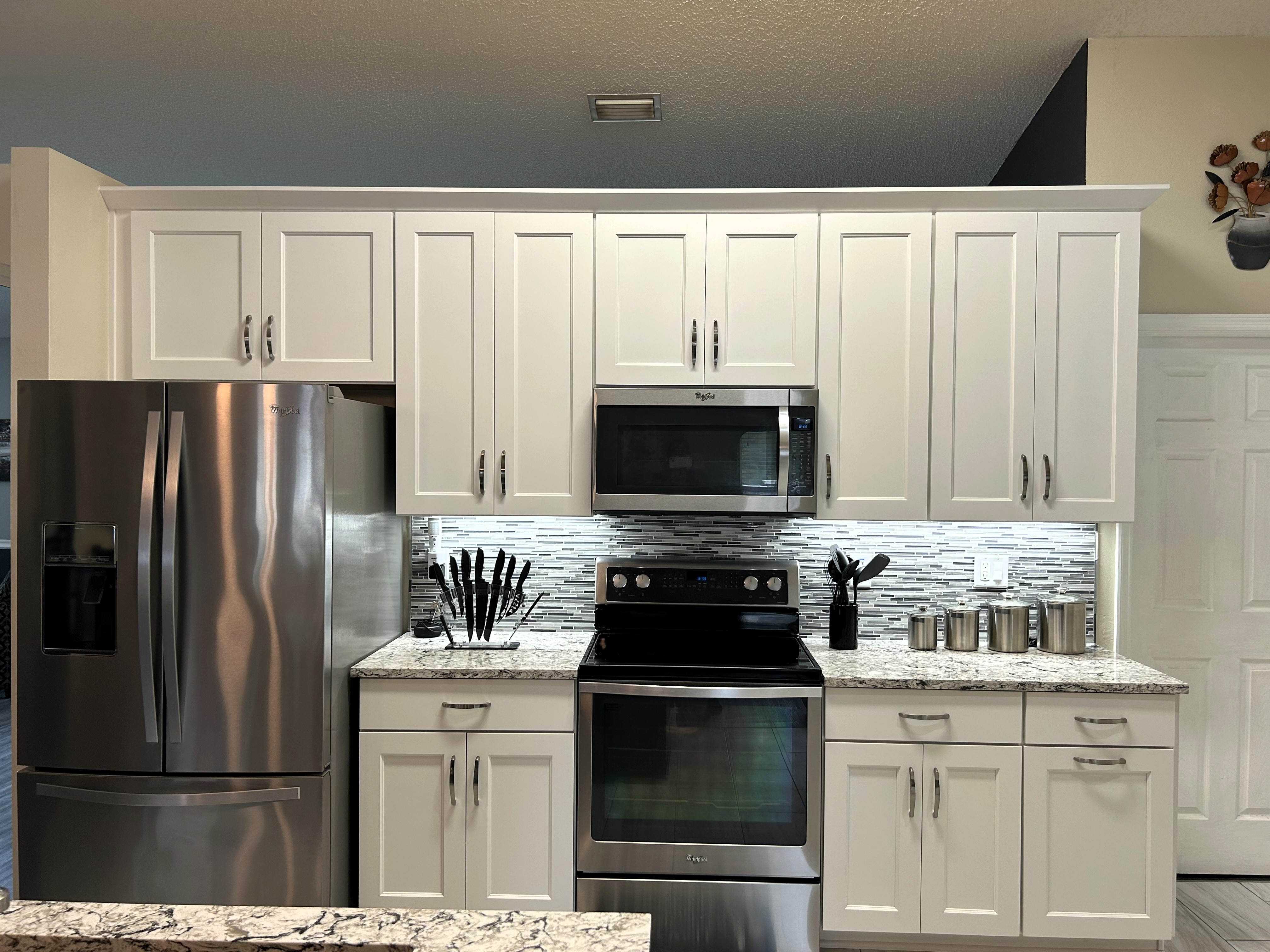 The LED underneath cabinetry lighting showcases the linear mosaic backsplash and compliments the Cambria quartz countertop.